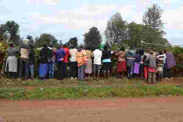 residedents watch from the fence as murungi body arrive