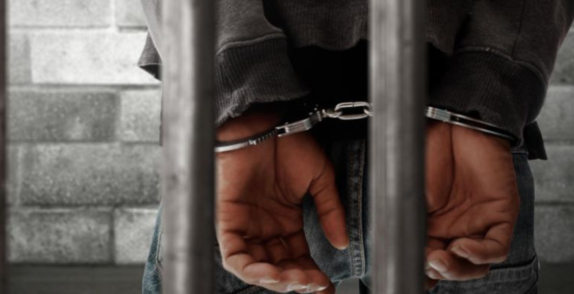 A Photo of a Man in Police Cuffs Man Sentenced to Death Set Free Over Girlfriend's Contradictory Evidence